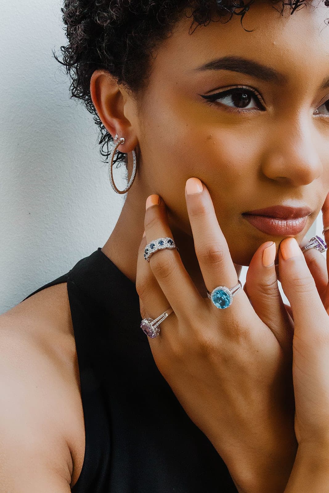 Diamond hoop earrings and gemstone rings worn together
